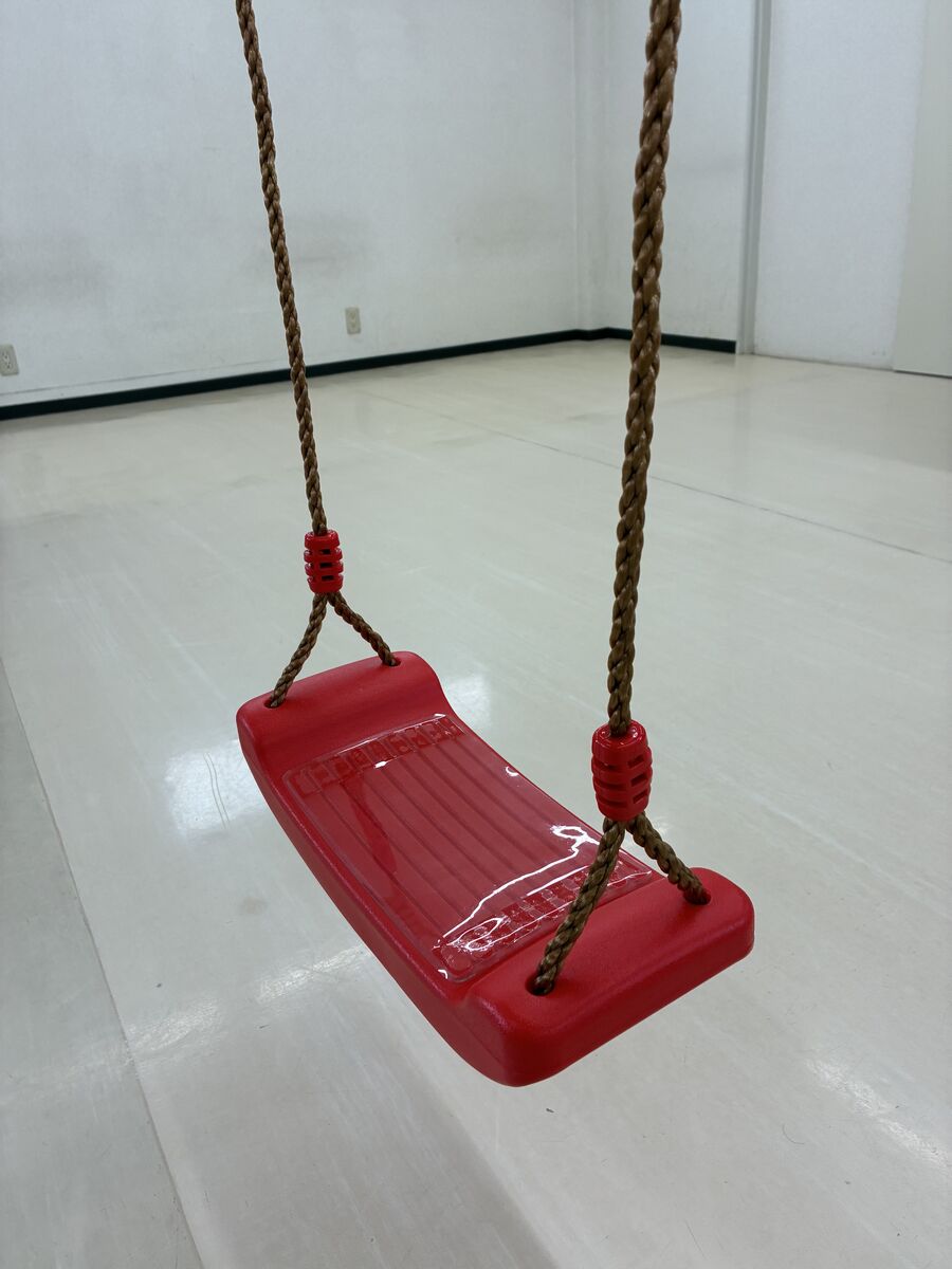 室内に設置された赤い座面のブランコ